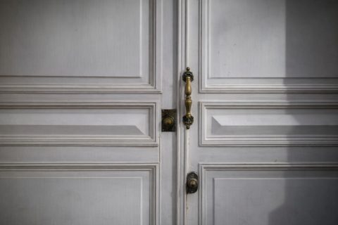 Close-up van een antieke messing deurklink op een klassieke witte binnendeur.