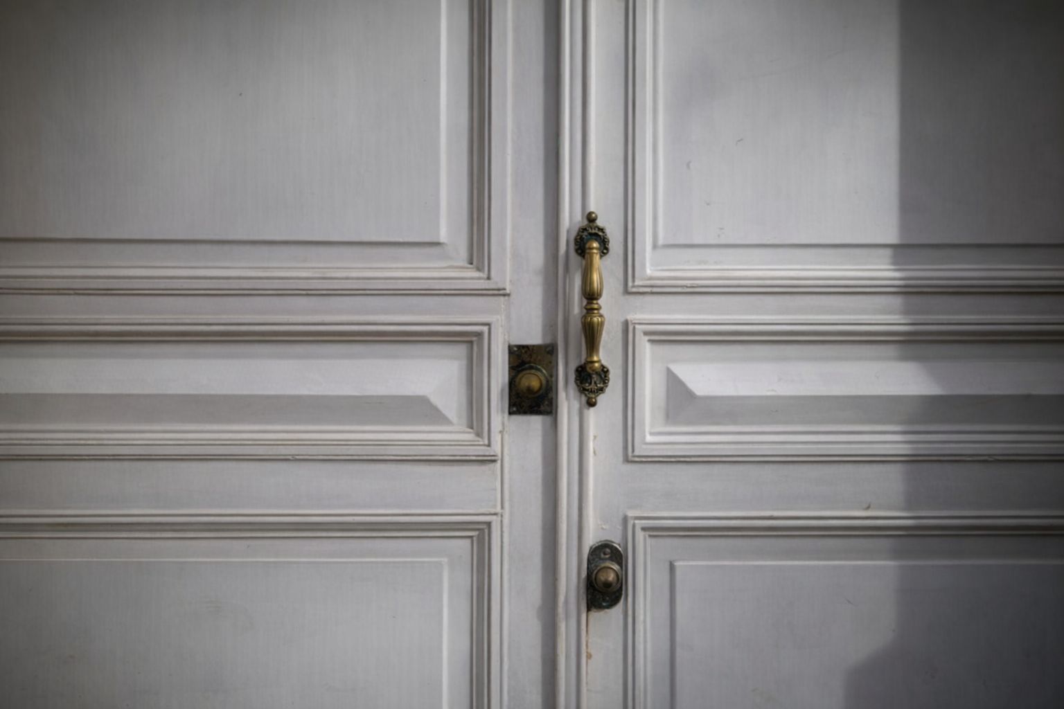 Close-up van een antieke messing deurklink op een klassieke witte binnendeur.