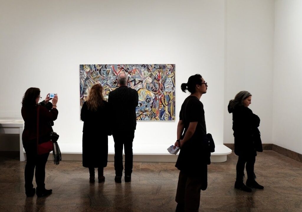 Bezoekers bekijken een kleurrijk schilderij in een helder verlichte galerie