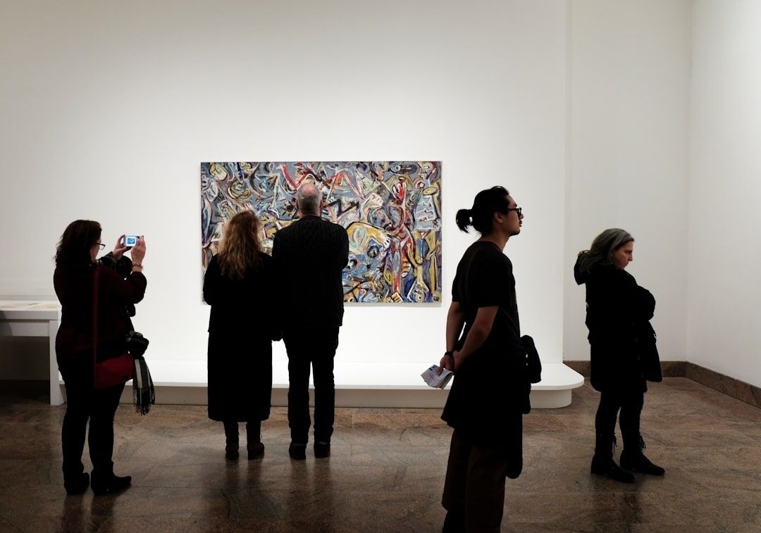 Bezoekers bekijken een kleurrijk schilderij in een helder verlichte galerie